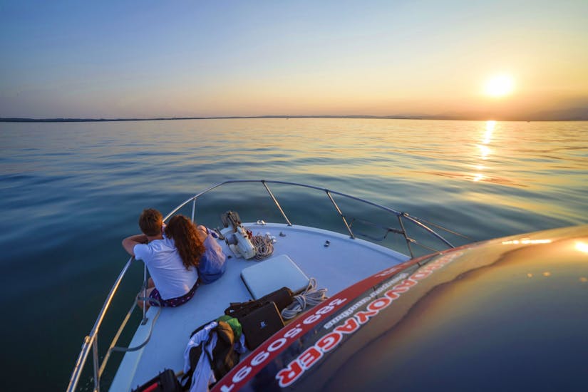 Ein Paar bewundert den Sonnenuntergang während der Bootsfahrt nach Sirmione mit Mittagessen und Schwimmen - ganztägig.