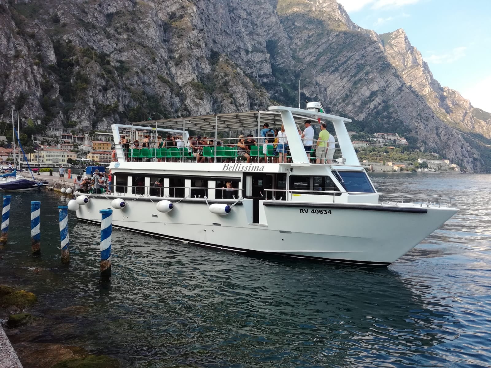 Uitzicht op een boot met op de achtergrond de rotsachtige bergen van het Gardameer tijdens de Volledige dag Boottocht van het Gardameer met Garda escursioni.