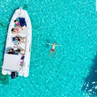 Foto dall'alto di un gommone e una persona che galleggia a stella in mare durante la gita in barca da Olbia all'isola di Tavolara con snorkeling con BlueSea Charter&Tour Olbia.