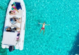 Foto dall'alto di un gommone e una persona che galleggia a stella in mare durante la gita in barca da Olbia all'isola di Tavolara con snorkeling con BlueSea Charter&Tour Olbia.
