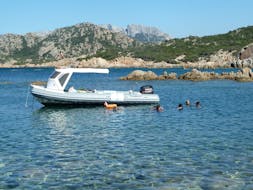 View of a dinghy in the clear sardinian waters where some people are snorkeling during the Boat Trip & Snorkeling to the Tavolara Marine Parc with Blue Way.