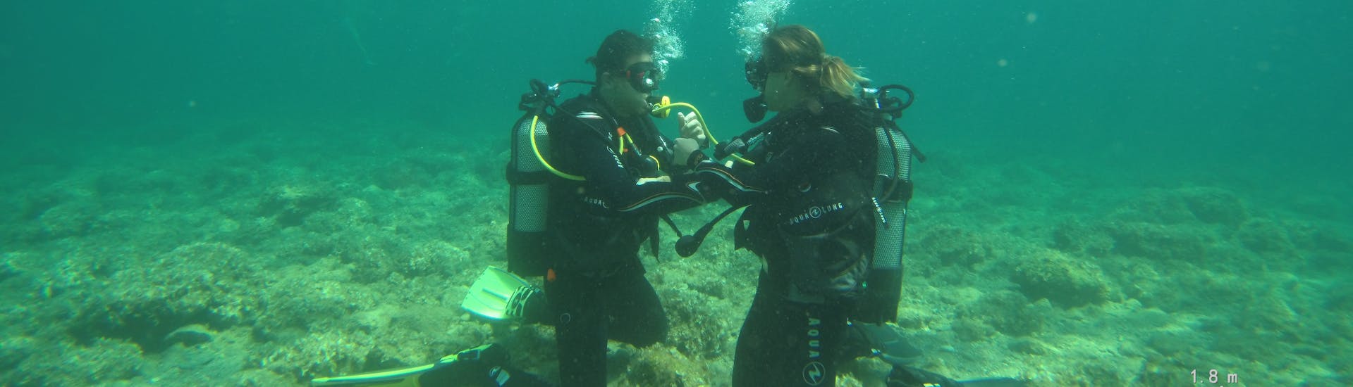 A couple diving during a PADI Open Water Diving Course in Kallithea for Beginners with Rhodes Diving Academy.