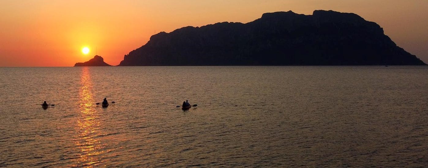 Vista de tres kayaks en el mar frente a una isla durante la excursión guiada en kayak al amanecer a la isla Proratora con café y snorkel con Ecosport Sardinia Olbia.