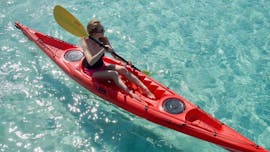 Vista de una mujer en un kayak en aguas cristalinas durante la excursión guiada en kayak por la mañana a la isla Proratora con frutas y snorkel con Ecosport Sardinia Olbia.