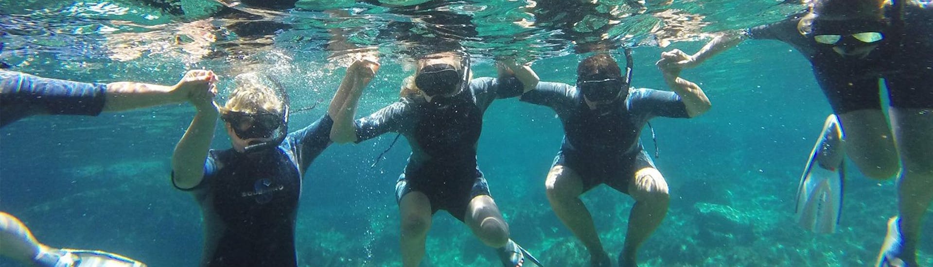 4 participants dans l'eau s'amusant durant la journée de plongée à Lia Beach à Mykonos avec GoDive Mykonos.