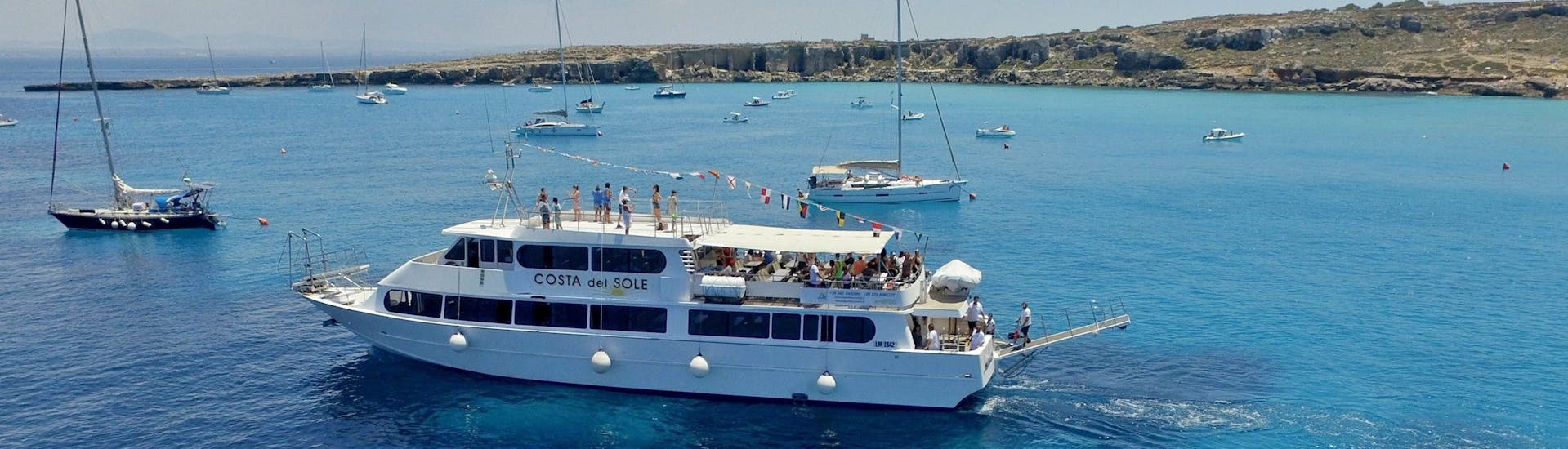 View of a boat in the clear waters of Favignana during the Boat Trip to Favignana's creeks with Egadi Escursioni.