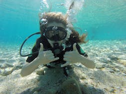 Jeune fille sous l'eau pendant le cours d'Open Water Diver pour débutants à Lia Beach à Mykonos avec GoDive Mykonos.