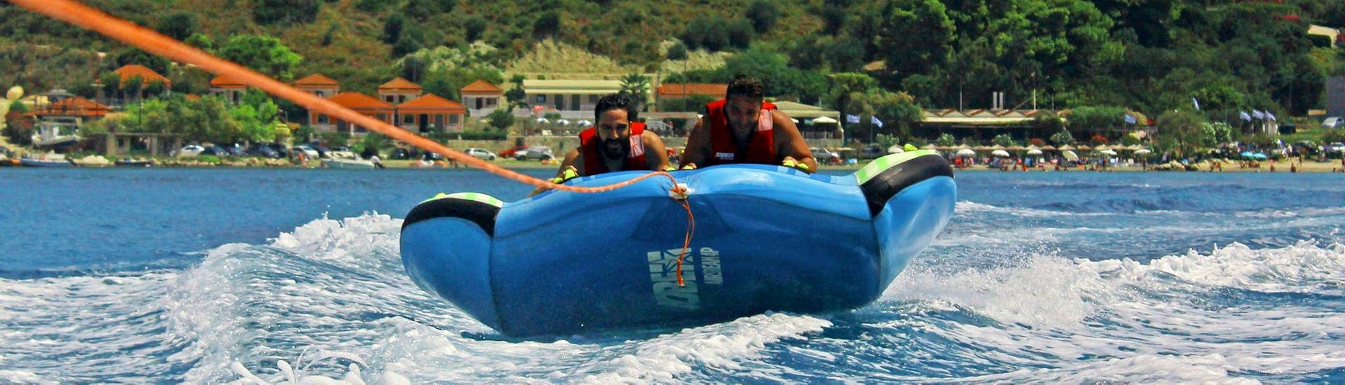 Deux hommes sont sur un Banana boat et autres bouées sur Alykes Beach à Zakynthos avec Alykes Water Sports Zakynthos.