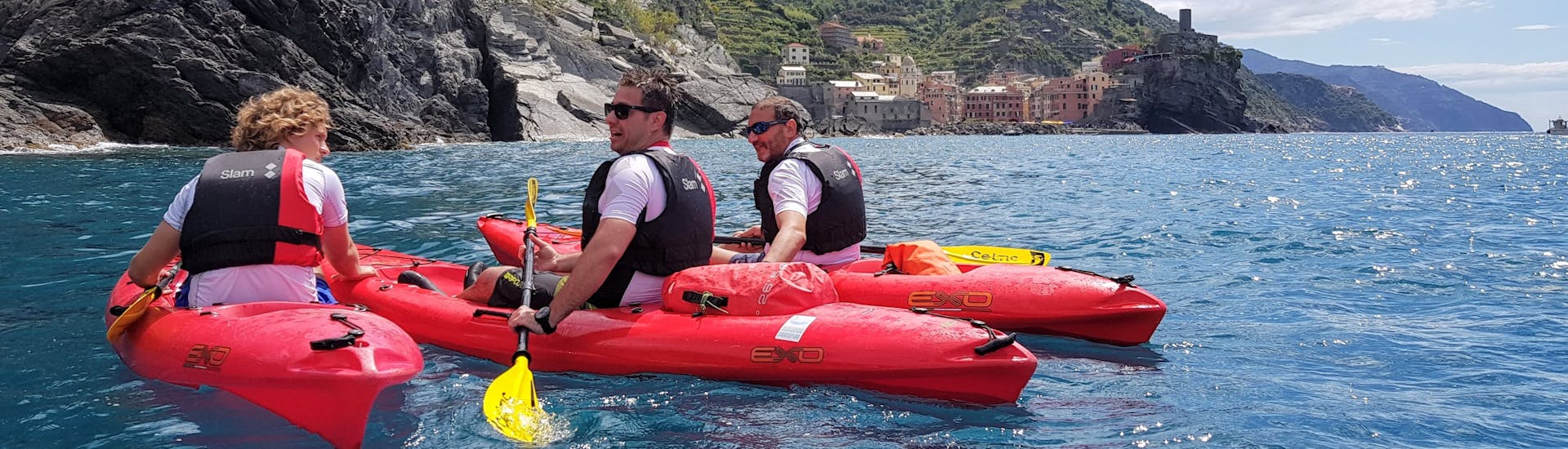 Drei Personen auf einem Kayak vor Vernazza bei der Kayaktour bei Sonnenuntergang in Cinque Terre mit Aperitif mit Outdoor Portofino.