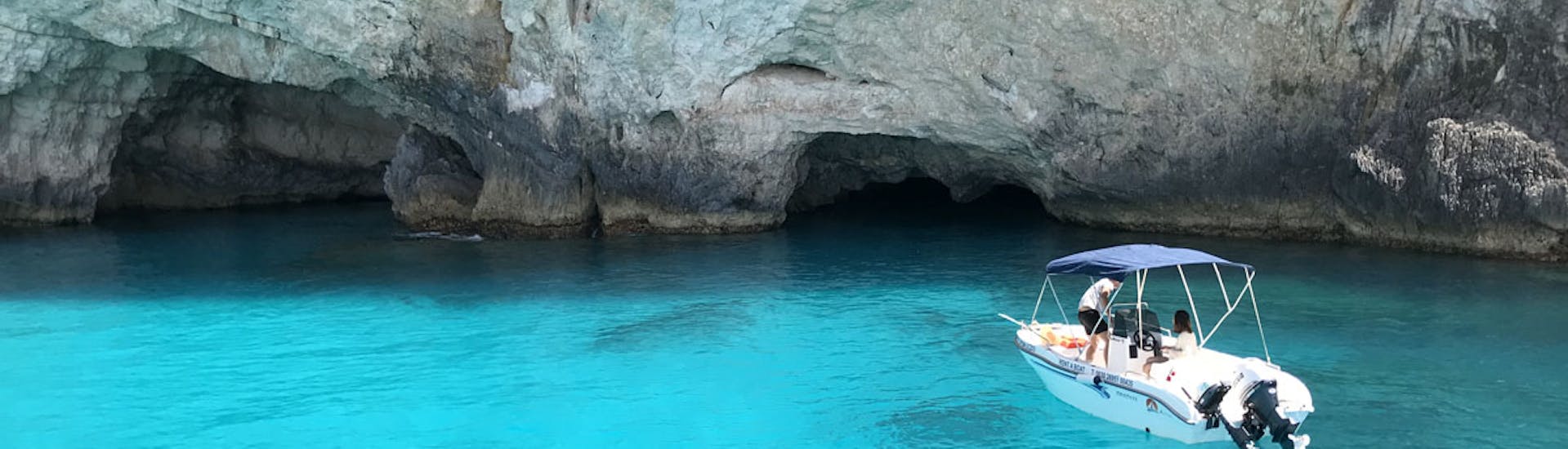 Private boat rented from Porto Vromi Maries anchored in front of small caves.