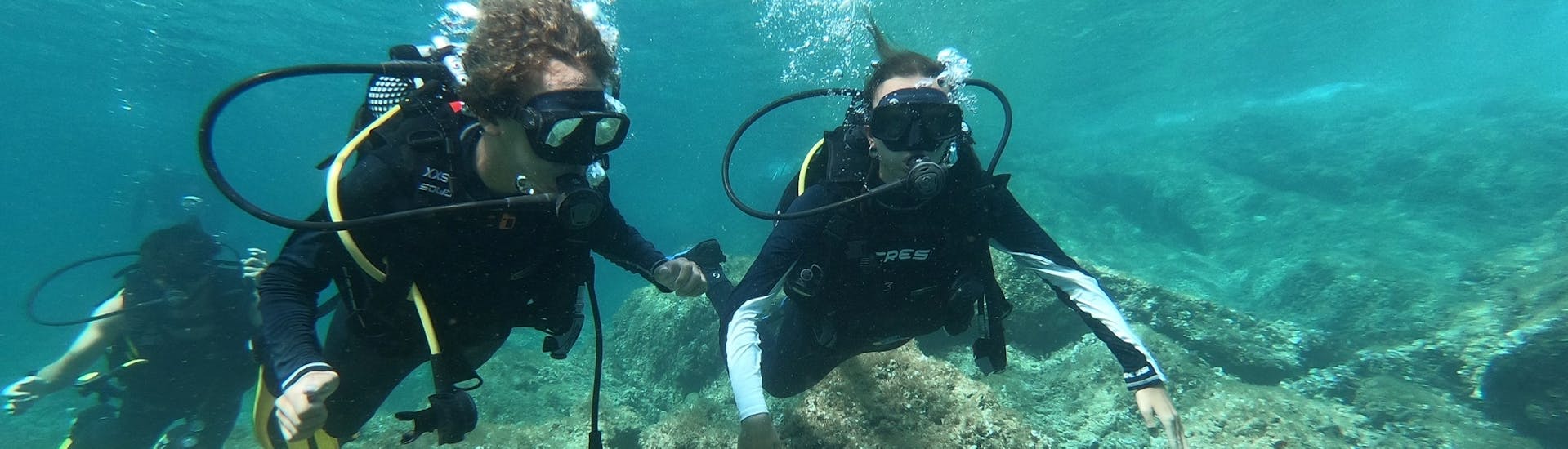 Zwei Freunde tauchen in den blauen Gewässern von Mallorca während eines PADI Discover Scuba Diving Kurses mit Albatros Diving in Cala Bona.