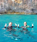 Zwei Mädchen im türkisfarbenen Wasser in Neoprenanzügen lächeln in die Kamera beim Schnorchelausflug vor der Küste von Santa Maria Navarrese.