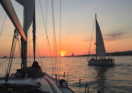 Two sailing boats navigating into the sunset during the Sunset Boat Trip from Lisbon on the Tagus River with Palmayachts Charters Portugal.