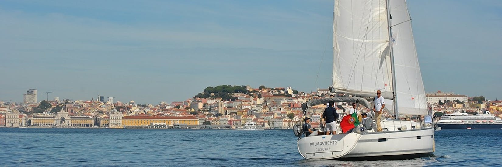 Un bateau en face de la vieille ville pendant la balade en bateau dans la vieille ville de Lisbonne sur le Tage avec Palmayachts Charters Portugal.