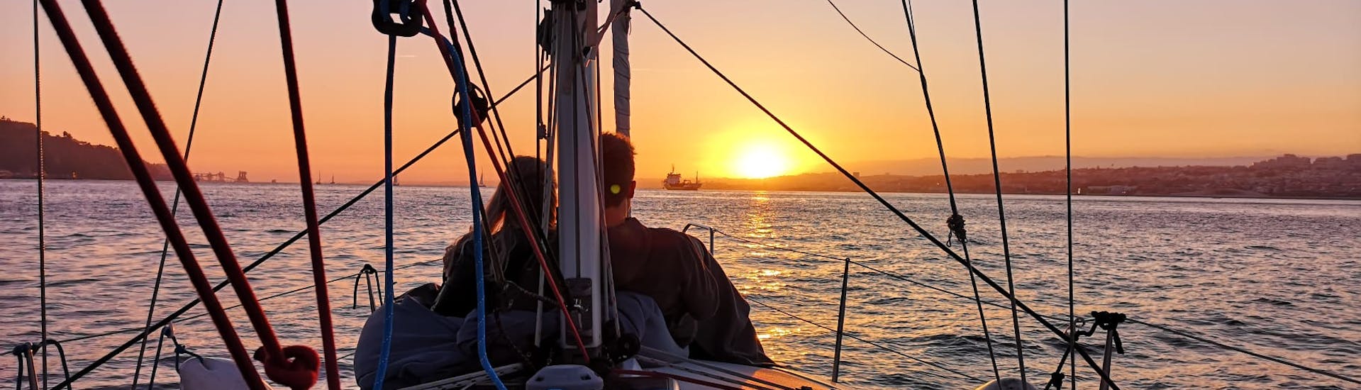 Una pareja disfrutando de la puesta de sol en un barco de Palmayachts Charters Portugal durante la excursión privada en barco al atardecer desde Cascais.