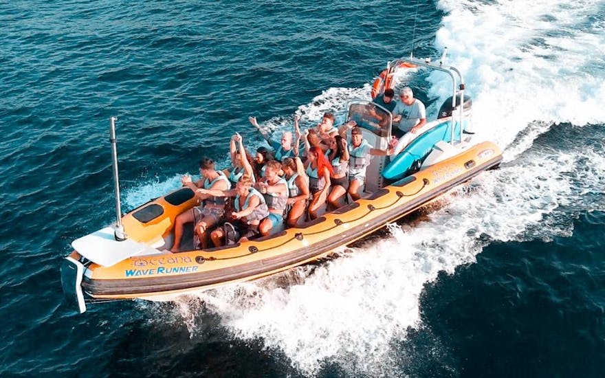 Participantes en una lancha rápida rodeados de velocidad y diversión rodeados de salpicaduras de agua en la Bahía de Alcúdia durante un viaje en barco desde Can Picafort al Parque Natural de Llevant con North Coast Adventure Mallorca.