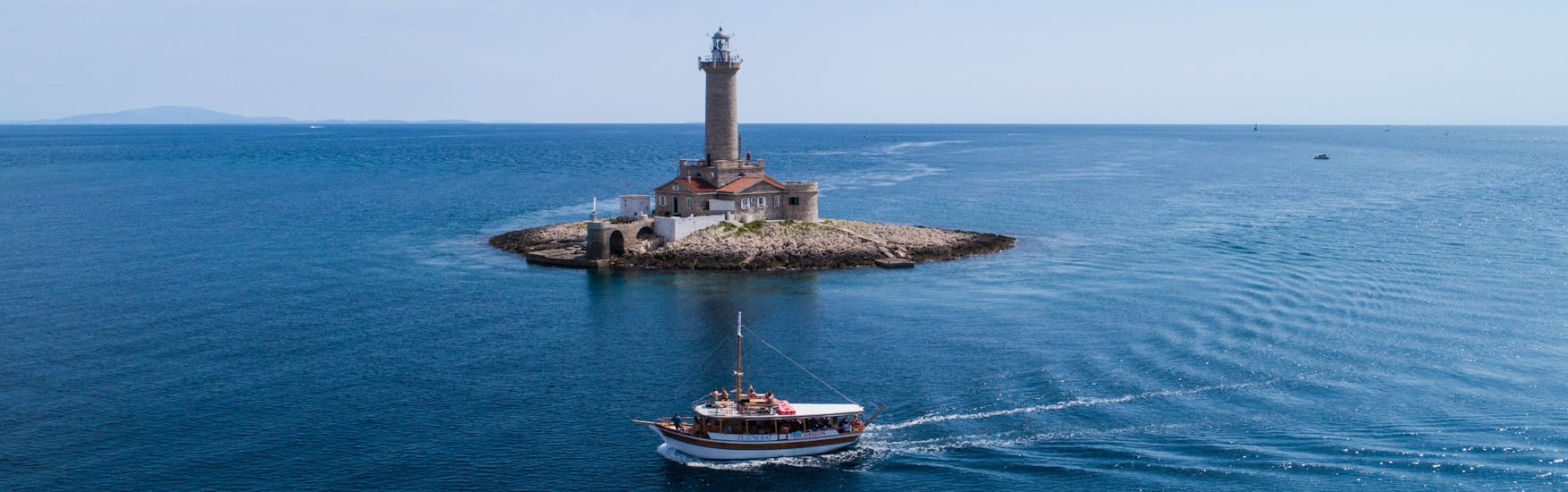 Bild des Bootes vor dem Porer Leuchtturm bei der Bootstour um die Halbinsel Medulin mit Mittagessen mit Tajana & Zlatni Rat Excursions Medulin.