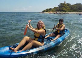 Two friends having fun while paddling along Alcudia Bay during a sea kayaking rental from Alcanada Beach with North Coast Adventure Mallorca.