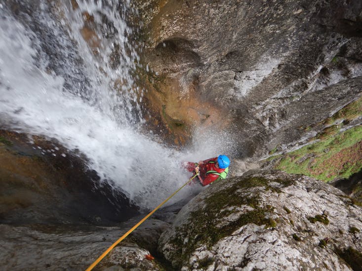 Ein Mann seilt sich durch einen Wasserfall ab während des Canyoning in der Taxaklamm für Fortgeschrittene - Waterfall Lovers mit CIA Canyoning in Austria Kössen.
