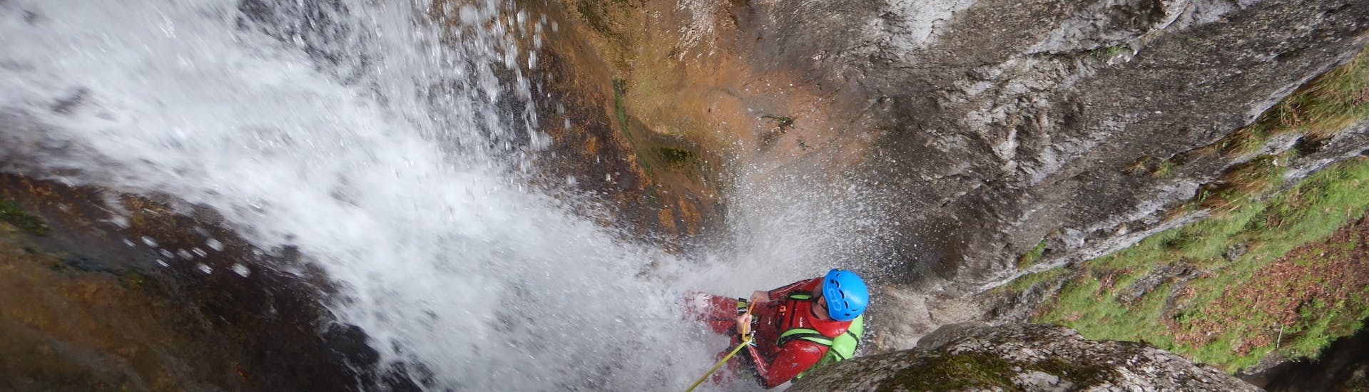 Ein Mann seilt sich durch einen Wasserfall ab während des Canyoning in der Taxaklamm für Fortgeschrittene - Waterfall Lovers mit CIA Canyoning in Austria Kössen.