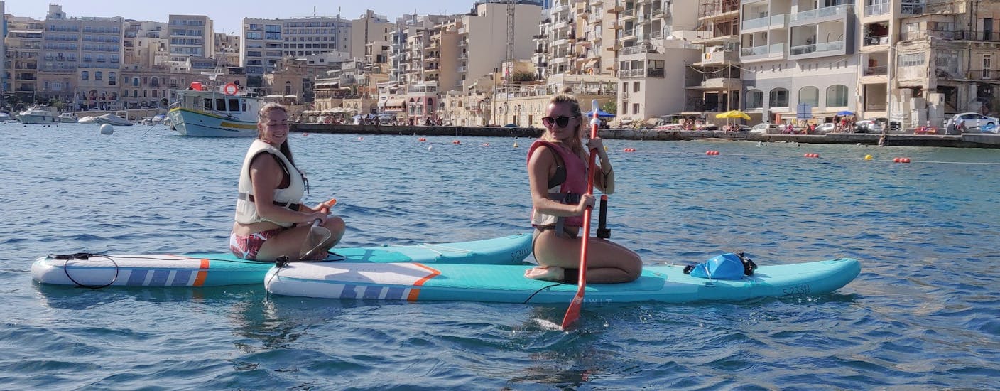 Two friends having fun during the SUP Hire in Spinola Bay in St. Julian's with Oki-Ko-Ki Banis Watersports St Julian's.