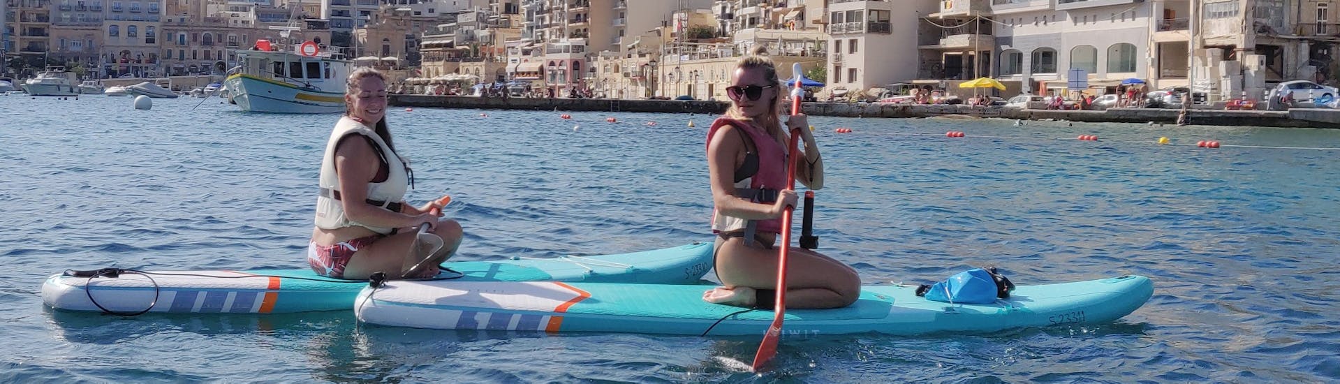 Two friends having fun during the SUP Hire in Spinola Bay in St. Julian's with Oki-Ko-Ki Banis Watersports St Julian's.