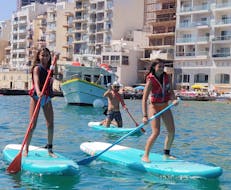 Participantes disfrutando del SUP en la bahía durante el alquiler de SUP en Spinola Bay en St. Julian's con Oki-Ko-Ki Banis Watersports St Julian's.