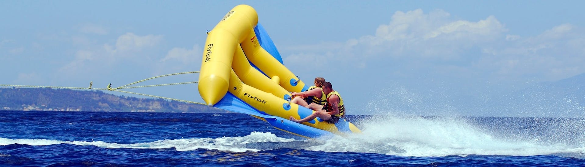 Freunde amüsieren sich mit einem Banana-Boat und weitere Spaßboote am Banana Beach mit Banana Watersports.
