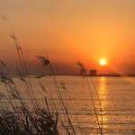 Il sole tramonta dietro Torre Chianca durante il giro in gommone al tramonto lungo la costa di Porto Cesareo con aperitivo con Vie del Mediterraneo Porto Cesareo.