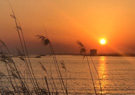 Il sole tramonta dietro Torre Chianca durante il giro in gommone al tramonto lungo la costa di Porto Cesareo con aperitivo con Vie del Mediterraneo Porto Cesareo.