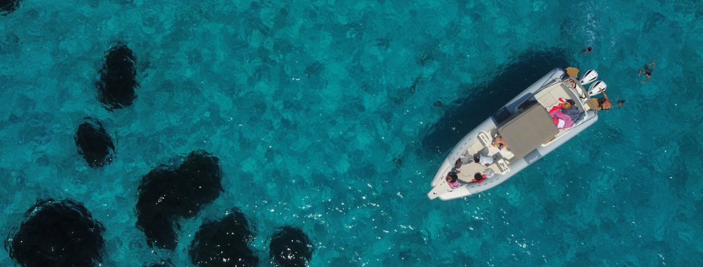 Vista di una barca che naviga nelle chiare acque delle Egadi durante il nostro giro in gommone privato a Marettimo e Levanzo con Passione Blu Trapani.