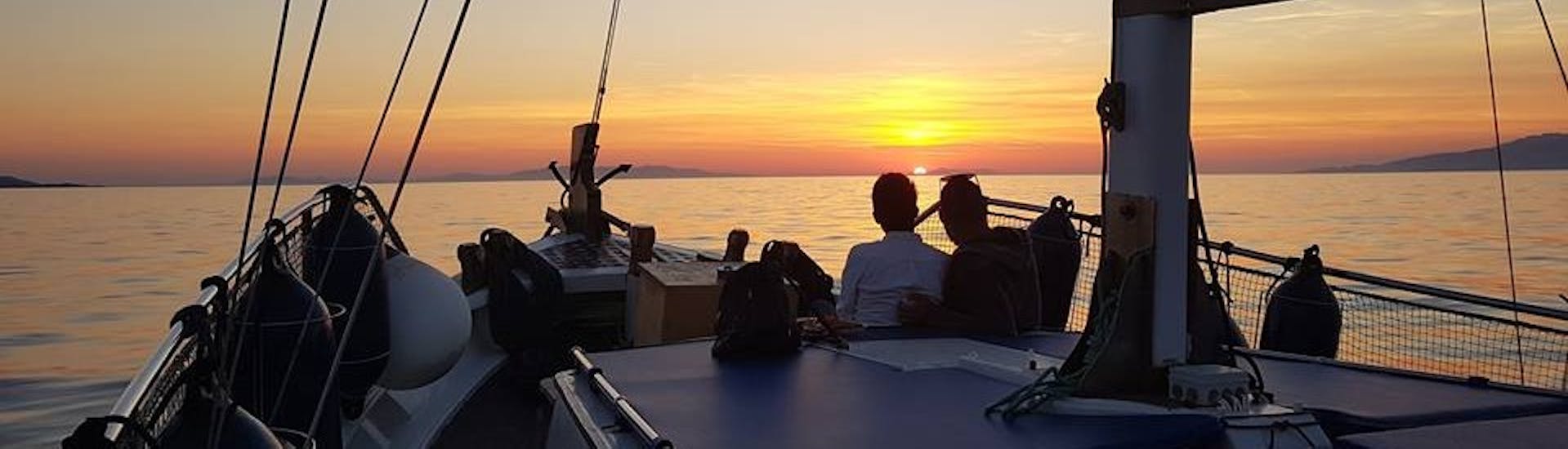 Due passegggeri ammirano il tramonto sul mare durante il Giro in barca lunco la Piccola Venezia e la città di Mykonos.