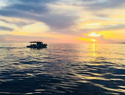Vue de la mer au coucher du soleil avec un bateau de Nord Est La Spezia pendant la Balade en bateau à Porto Venere & ses îles avec Snorkeling.