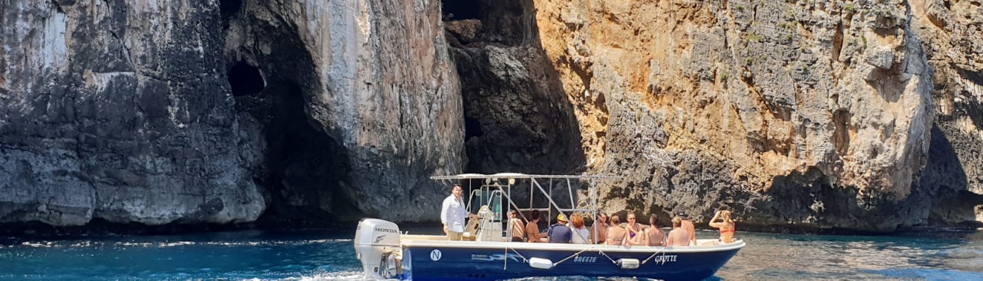 Vista di una barrca che naviga vicino alla costa rocciosa di Santa Maria di Leuca durante il giro in barca alle grotte dell'Adriatico da Santa Maria Leuca con Leuca Due Mari.