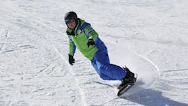 Un maestro privato di snowboard della scuola di sci Alpinsport Obergurgl mostra come fare una curva.