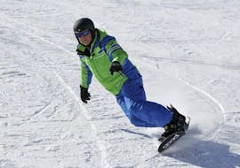 Un maestro privato di snowboard della scuola di sci Alpinsport Obergurgl mostra come fare una curva.