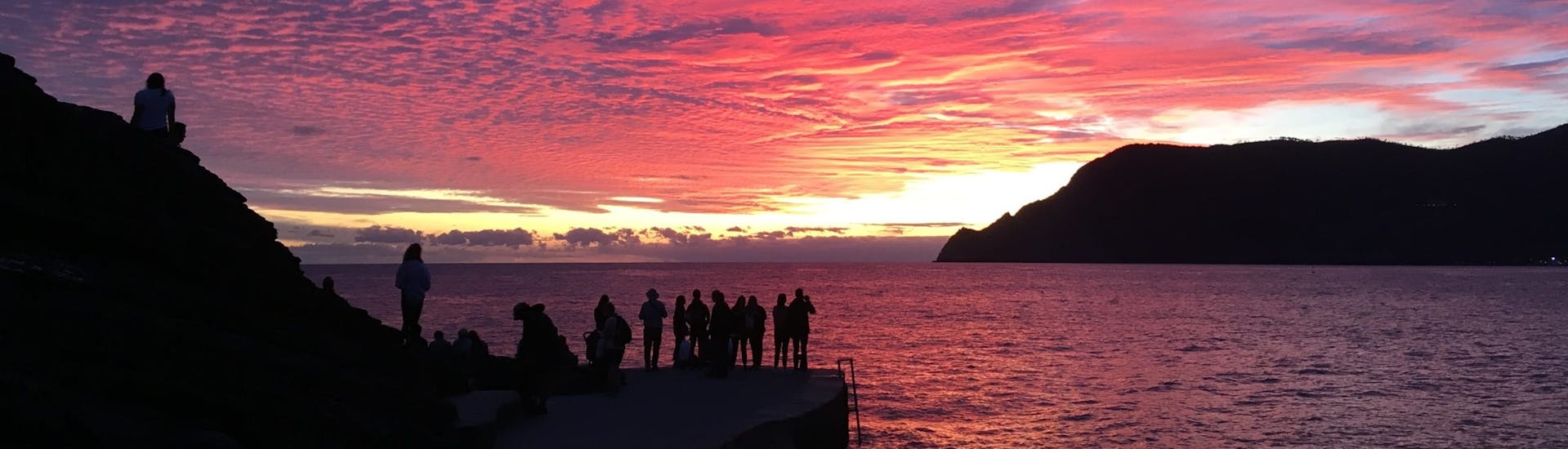 Eine Gruppe von Menschen bewundert das Meer bei Sonnenuntergang während einer privaten Bootstour nach Porto Venere und zu den Inseln mit Schnorcheln.