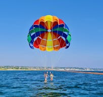 A couple is preparing to fly at a height of 60 metres with a parasailing in Torre Vado with Rosa dei Venti Escursioni.