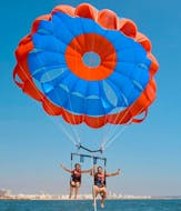 Zwei Freunde genießen einen Flug beim Parasailing im  Vilamoura Marina an der Algarve mit dem Vilamoura Watersports Centre.