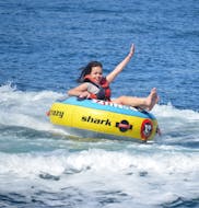 Ein Mädchen hat Spaß auf dem Banana Boat und weiteren Schlauchbooten im Yachthafen von Vilamoura mit dem Vilamoura Watersports Centre.