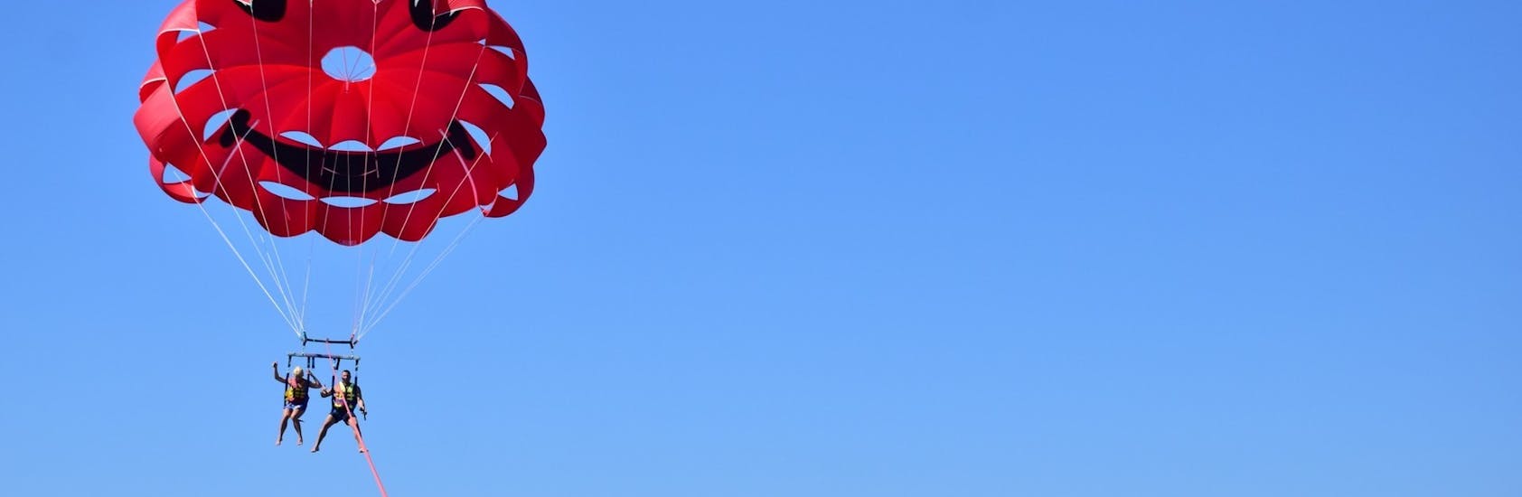 Immagine di persone in aria durante l'attività di parasailing con St. Nicholas Beach Watersports Zakynthos.