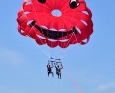 Couple hanging onto the parachute during parasailing with St. Nicholas Beach Watersports Zakynthos.