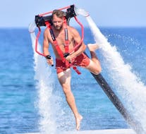 Ein Mann schwebt mit dem von St. Nicholas Beach Watersports Zakynthos gemieteten Flypack auf dem Rücken über dem Wasser.