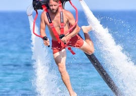 Un uomo si libra sopra l'acqua con il flypack sulla schiena, noleggiato da St. Nicholas Beach Watersports Zakynthos.
