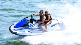 Twee deelnemers hebben plezier, rijdend op een jet ski op snelheid, rond de baai van Estepona, terwijl ze een jet ski tour doen met South Olé Sails Estepona.