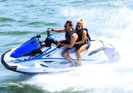 Two participants having fun, driving a jet ski at speed, going around the Bay of Estepona, while doing a jet ski tour with South Olé Sails Estepona.