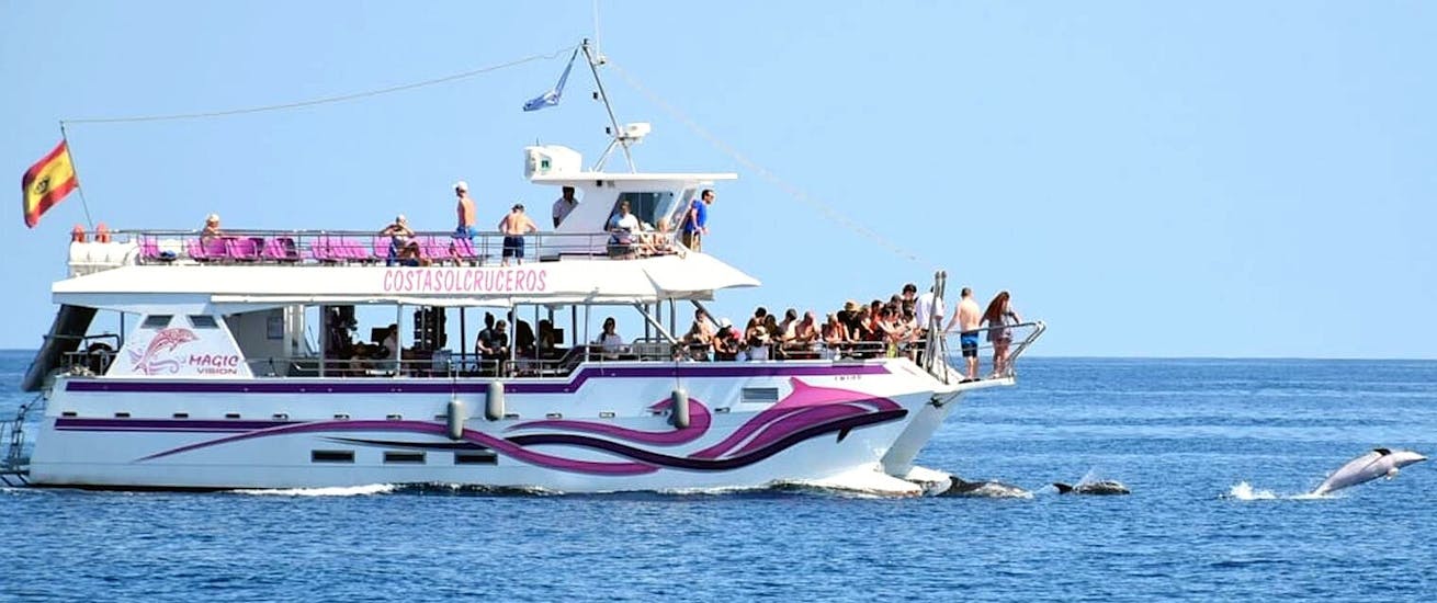 Il catamarano Magic Vision in crociera nella baia di Benalmadena con i partecipanti che si divertono a bordo, durante una gita in catamarano a Benalmádena con avvistamento dei delfini con Costasol Cruceros.