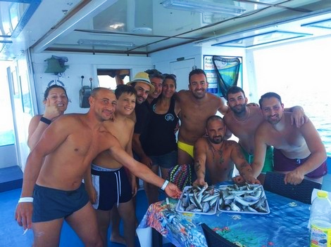 Picture of a group of people and their catch on a boat from Pescaturismo Vivereilmare Porto Cesareo during the Private Boat Trip in Porto Cesareo with Fishing Experience.