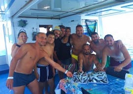Picture of a group of people and their catch on a boat from Pescaturismo Vivereilmare Porto Cesareo during the Private Boat Trip in Porto Cesareo with Fishing Experience.
