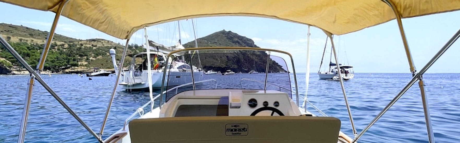 EL moderno barco MARETI 600 OPEN surcando las azules aguas de la bahía de roses durante un alquiler de embarcación en la Costa Brava para hasta 7 personas con licencia con Maxi Boats.